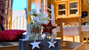 A rustic wooden table with a decorative centerpiece featuring white flowers and red stars, set against a window with curtains. - Z-Chalet Mitoyen 6A., Z-Chalet Mitoyen 6A. (Mont-Saxonnex)
