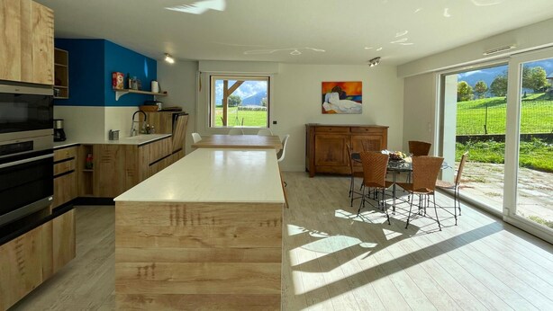A modern kitchen with wooden cabinets, a large island, and a dining area with wicker chairs. - Beautiful villa with mountain view, Beautiful villa with mountain view (Châteauneuf)