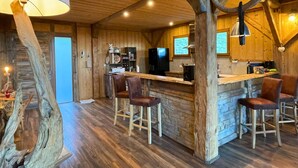 A rustic wooden interior with a bar area, wooden stools, and a stone wall. - Luxurious 5 bedroom chalet, Luxurious 5 bedroom chalet (Brizon)