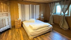 A wooden-paneled room with a bed, a nightstand, and a window with curtains. - Luxurious 5 bedroom chalet, Luxurious 5 bedroom chalet (Brizon)
