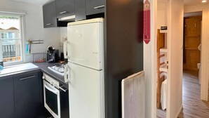 A compact kitchen with a refrigerator, stove, and coffee maker. - Spacious mobile home + terrace !, Spacious mobile home + terrace ! (Verchaix)