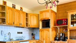 A wooden kitchen with a dining table and chairs, a microwave, and various kitchen appliances. - Z-Chalet Mitoyen 5A., Z-Chalet Mitoyen 5A. (Mont-Saxonnex)