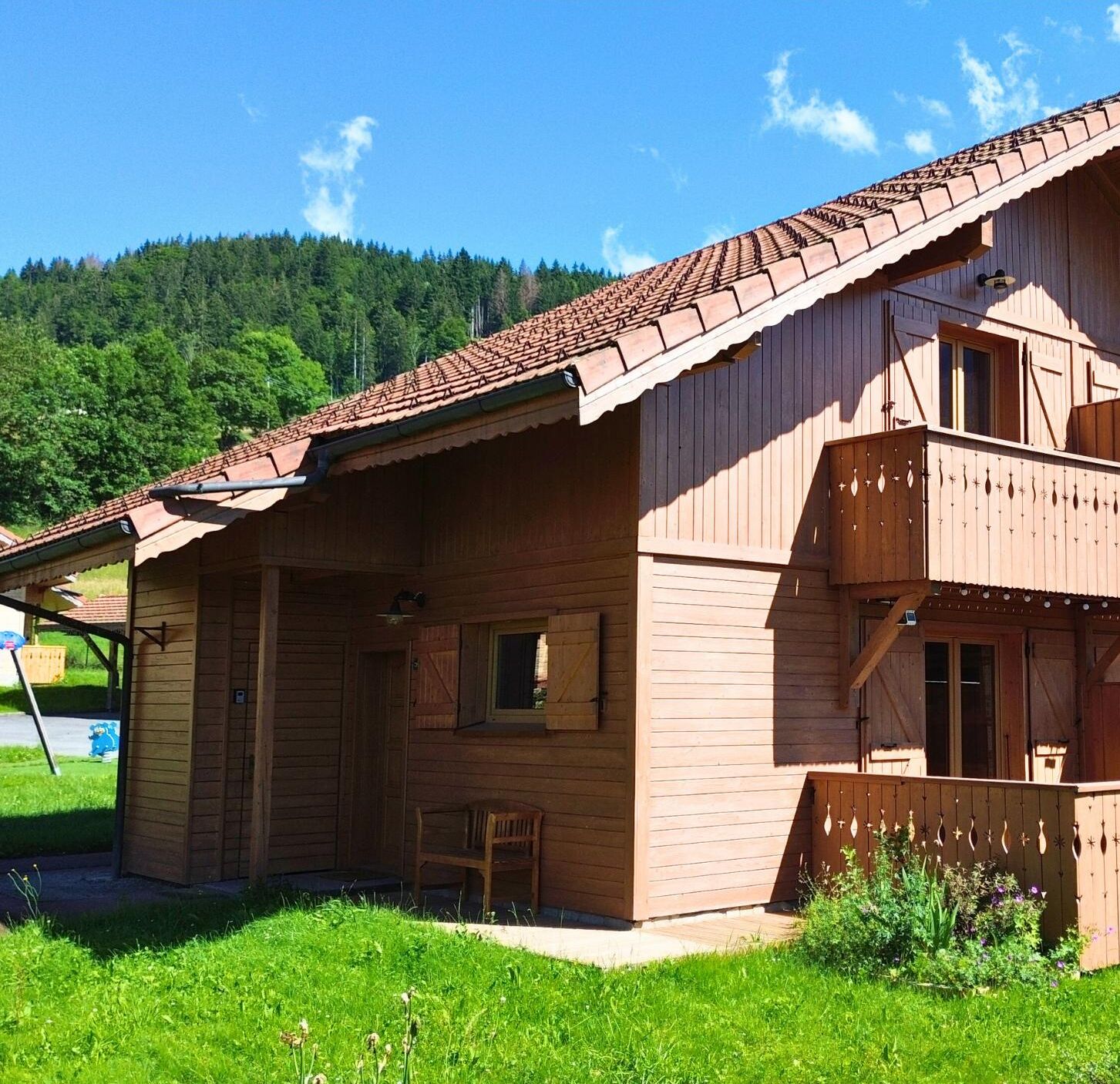 Un chalet en bois doté d’un toit à pente, d’un balcon et d’un petit espace porche.