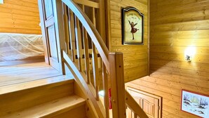 Un escalier en bois avec une rampe, des murs en bois et un tableau encadré représentant une danseuse.