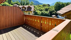 Een houten terras met uitzicht op een berg en een huis.