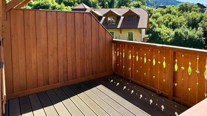 Een houten terras met uitzicht op een berg en een huis.