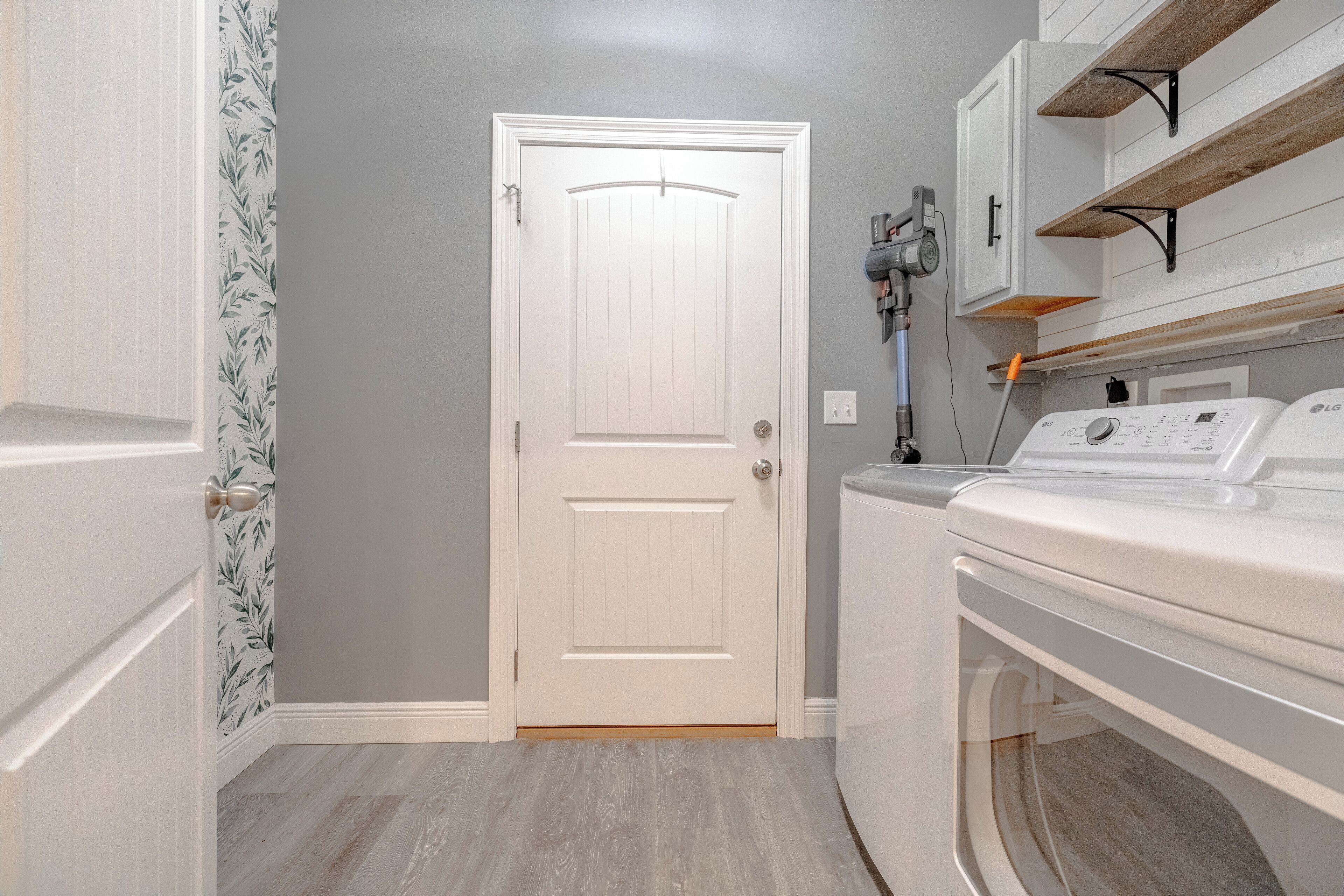 A laundry room with a white door, a washing machine, and a drying rack.
