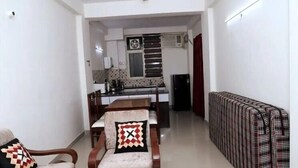 A compact living space with a dining area, kitchenette, and a sofa. - Shree Jee Dham (Mathura)