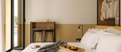Una camera d'albergo con un letto, un vassoio con frutta, un libro e vista sull'esterno.