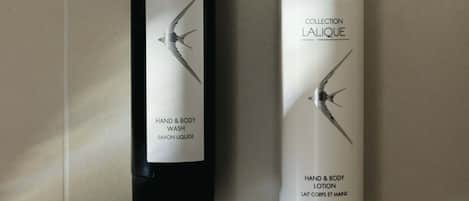 Dos botellas de loción corporal y para manos Collection L'ALIQUE sobre un suelo de baldosas.