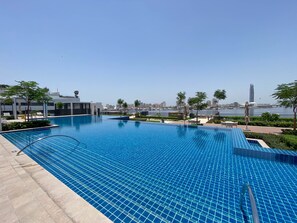 Een buitenzwembad, parasols bij het zwembad en ligstoelen