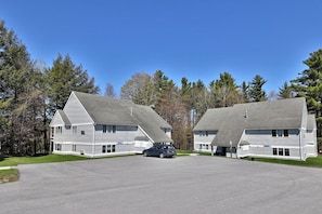 A two-story building with a symmetrical design, featuring a central driveway and a car parked in front. - Charming Killington Center Studio Condo on the Bus Route. Discounted Ski Rentals. Pool. (Killington)