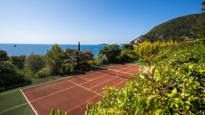 A tennis court with a clear view of the sea and a hilly landscape. - VILLA LA PETITE RESERVE VI4416 By Riviera Holiday (Eze)