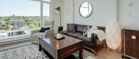 Ein modernes Wohnzimmer mit einer Ledersofa, einem Holztisch und einem großen Fenster mit Blick auf die Stadt.