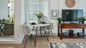 Un espace repas moderne avec une table ronde, des chaises blanches et un vase de fleurs.