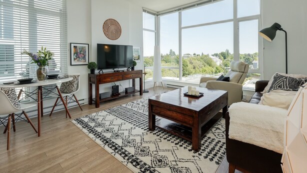 Un salon moderne comprenant un grand téléviseur, un canapé, une table basse et un coin repas avec des chaises et une table.
