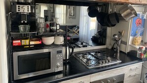 Ett kök med en gasspis, en mikrovågsugn och en kaffebryggare.