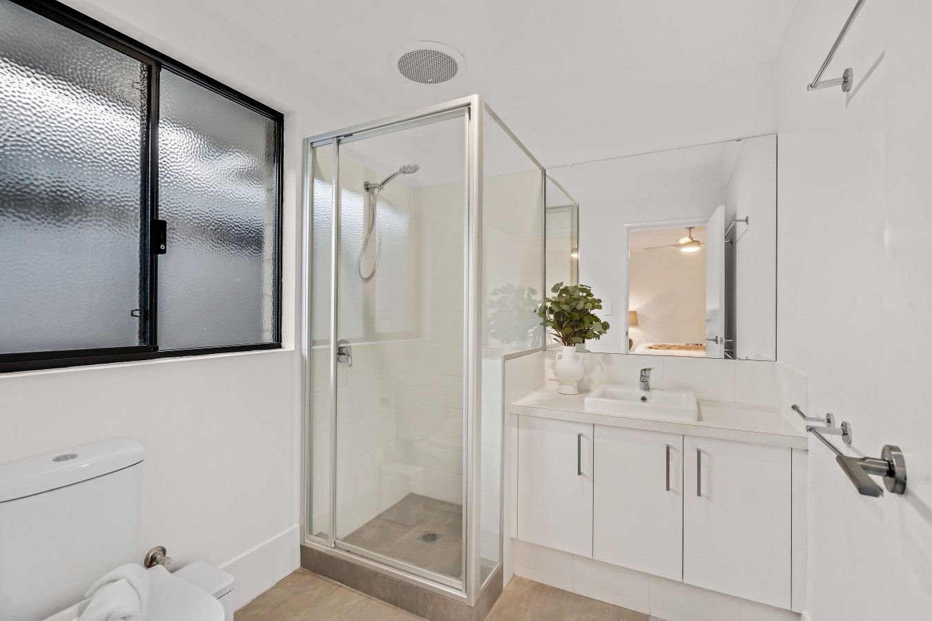 A modern bathroom with a glass-enclosed shower, a white sink, and a mirror above it.