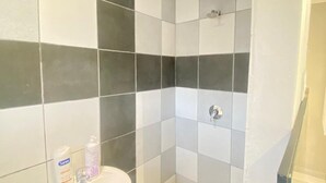 Een badkamer met een zwart-wit schakeerd motief vloer, een witte wastafel en een douchehoek.
