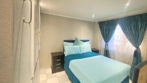 Een slaapkamer met een bed, een nachtkastje en een garderobe.