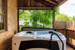 Un bain à remous situé dans un espace extérieur abrité, entouré d’une clôture en bois et doté d’une fenêtre.