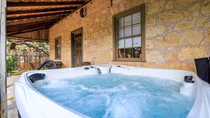 Un bâtiment en pierre doté d’un jacuzzi situé sous un toit en bois.