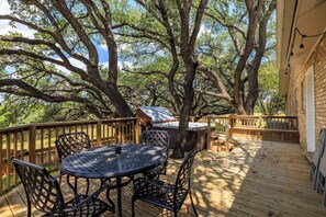 An outdoor deck with a round table and chairs, surrounded by trees.