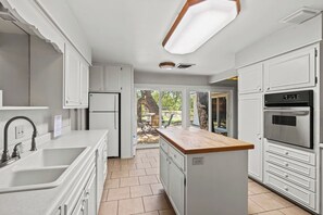 Eine moderne Küche mit weißen Schränken, einem eingebauten Backofen und einer großen Kücheninsel mit einer Holz Arbeitsplatte.