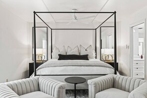 Een hotelkamer met een bed met hemel, een kleine ronde tafel en twee gestoffeerde fauteuils.