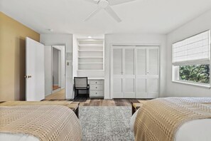 Ein Schlafzimmer mit einem Bett, einem Schreibtisch, einem Stuhl, einem Kleiderschrank und einem Fenster.