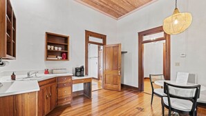 A kitchen with wooden cabinets, a white countertop, and a hanging light fixture. - Danz Haus | Historic Home | Baron's Creek (Fredericksburg)