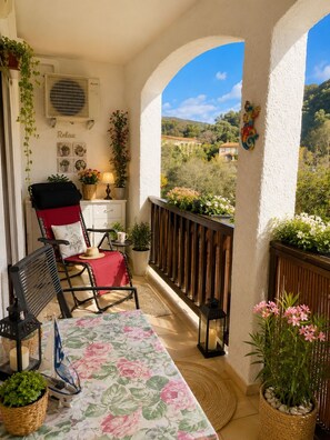 Ein Balkon mit Tisch, StĂŒhlen, Topfpflanzen und Blick auf die Landschaft.