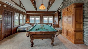 A room with a pool table, wooden walls, a stone fireplace, and large windows. - Celestial View (Blowing Rock)