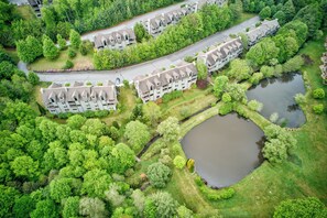 Una vista aerea di una zona residenziale con edifici a più piani, una strada tortuosa e uno stagno.