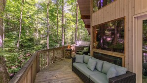 A wooden deck with a sofa and a fire pit, surrounded by a forest. - Gait to Paradise (Boone)