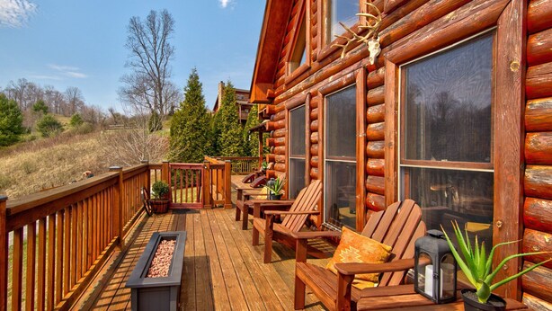 Eine Blockhütte mit einer Terrasse, Sitzgelegenheiten im Freien und einer Feuerstelle.