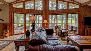 A spacious living room with a large wooden ceiling, a leather sofa, a coffee table, and a television. - Love to Beech (Banner Elk)