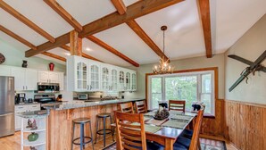 A kitchen with white cabinets, a wooden island, and a dining area with a table and chairs. - Love to Beech (Banner Elk)