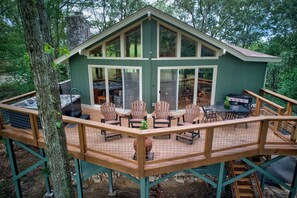 A wooden deck with a dining area, a grill, and a stone fireplace. - Love to Beech (Banner Elk)