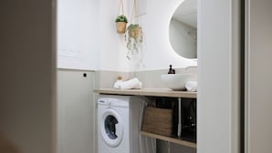 A compact laundry room with a washing machine, a sink, and a mirror. - BOHO Studio - Augarten City Apartment (Vienna)