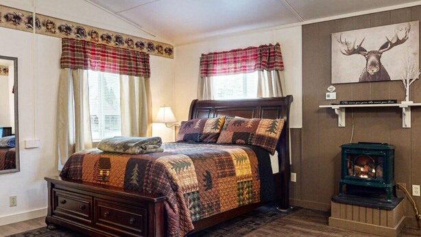 A bedroom with a bed, a fireplace, and a deer painting on the wall. - Bear`s Den *ATV Access*Walk to Town/Bars/Restaurants*A/C*Pet Friendly (Greenville)