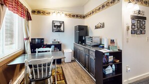A compact kitchen with a dining table, chairs, a microwave, a refrigerator, and a small oven. - Bear`s Den *ATV Access*Walk to Town/Bars/Restaurants*A/C*Pet Friendly (Greenville)