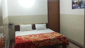 Een hotelkamer met een bed, een plafondventilator, een deur en een aan de muur bevestigd schilderij.