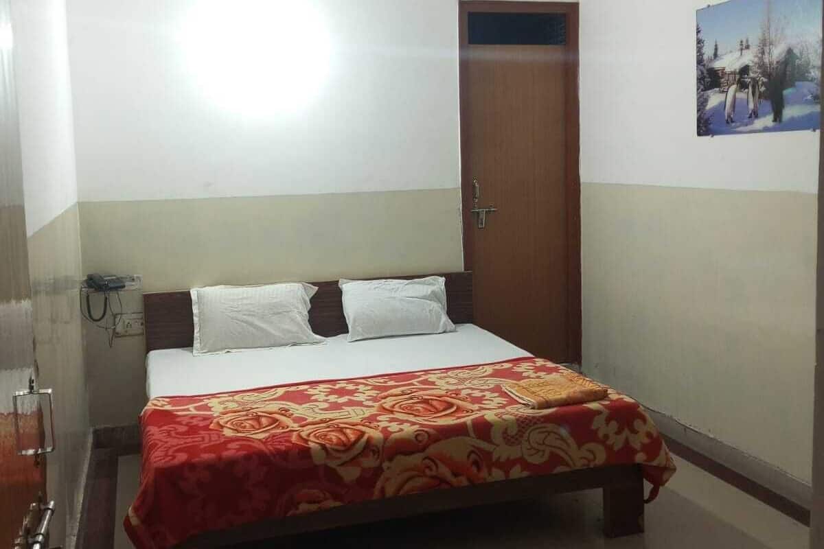 A hotel room with a bed, a ceiling fan, a door, and a wall-mounted picture.