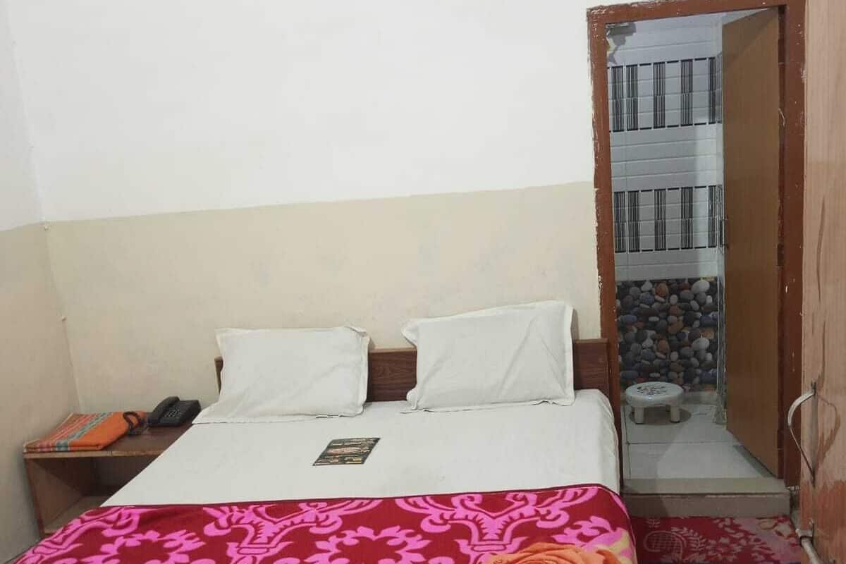 A bedroom with a bed, a bedside table with a phone, and a door leading to a balcony.