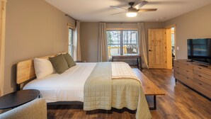Una camera da letto con un letto, una scrivania, una TV e un comò in legno.