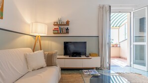 A living room with a sofa, a coffee table, a TV on a stand, and a bookshelf. - Emma House, Terrace and Sea View, Moneglia (Moneglia)