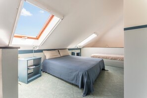 A bedroom with a skylight, a bed with a blue bedspread, a bedside table with a lamp, and a small shelf. - Emma House, Terrace and Sea View, Moneglia (Moneglia)