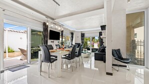 A modern dining area with a glass table, black chairs, and a TV mounted on the wall. - Villa Bianco Nero With Pool (Pula)