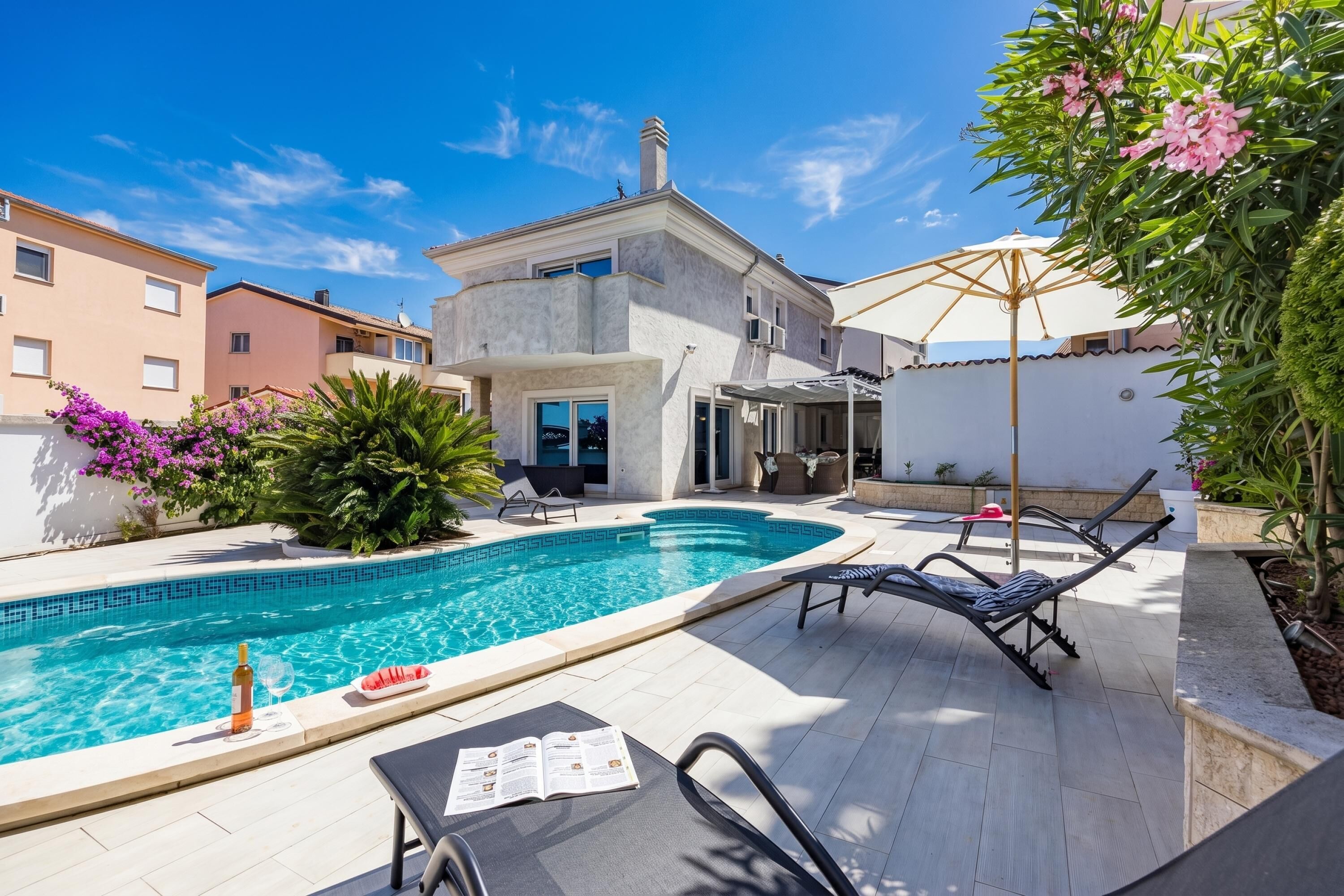 A swimming pool with lounge chairs, a book, and a bottle.